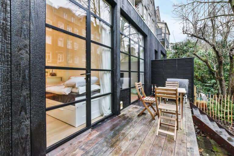 Antigua Guatemala Airbnb - Outdoor terrace with wooden tables and chairs beside modern glass doors.