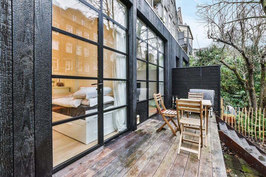 Antigua Guatemala Airbnb - Outdoor terrace with wooden tables and chairs beside modern glass doors.