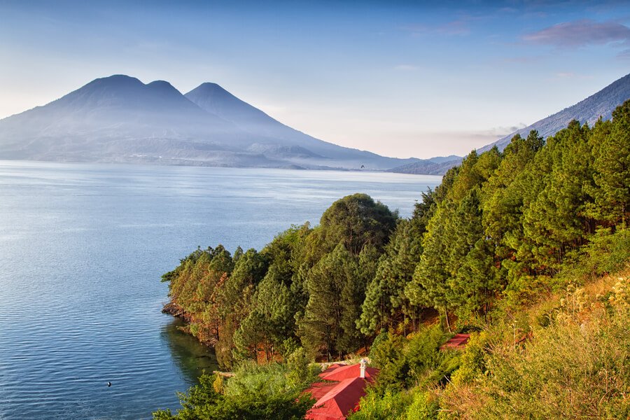 Panoramic view of Lake Atitlán with lush green hills and majestic volcanoes.