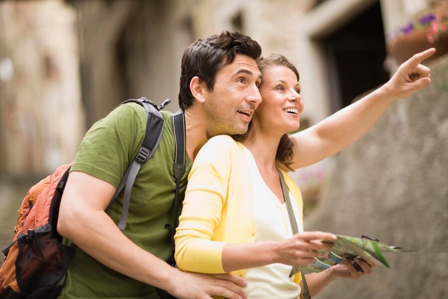 What to do antigua guatemala - Happy couple exploring Antigua Guatemala with a city map and backpacks.